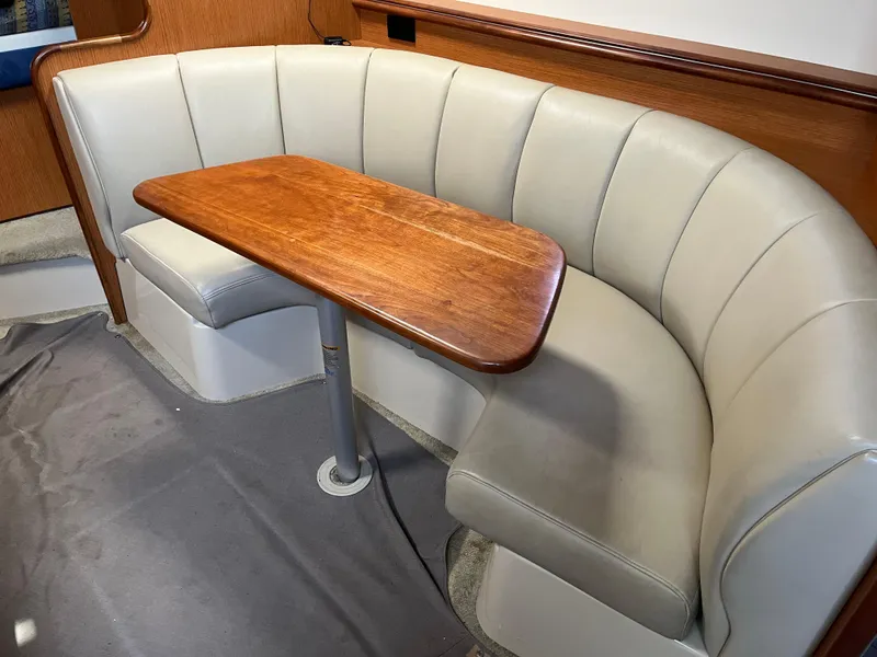 Slide: The Image of 2004 Cruisers Yachts 320 Express interior with curved seating and wooden table. - 18