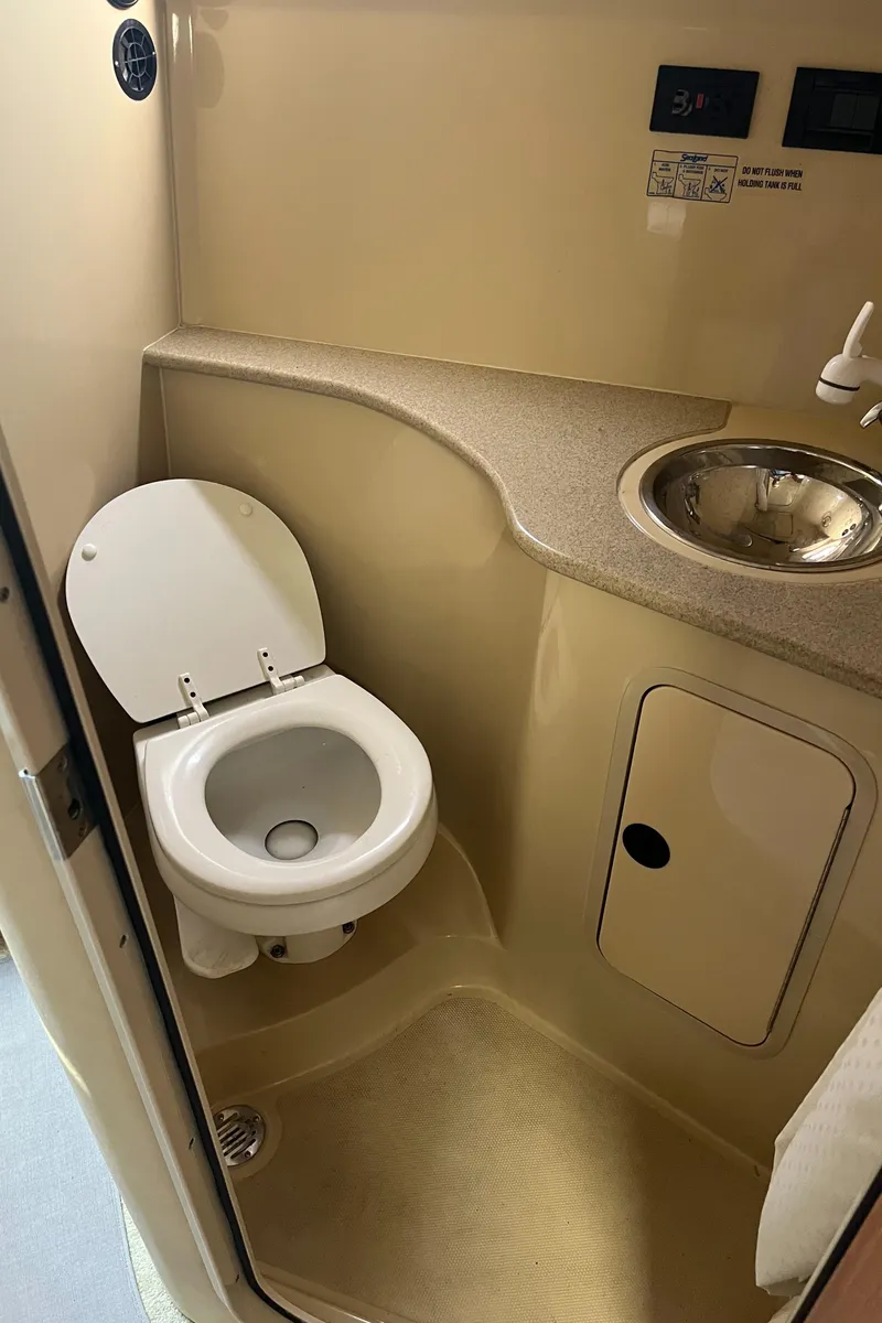 Slide: The Image of 2004 Cruisers Yachts 320 Express bathroom with toilet, sink, and storage. - 28