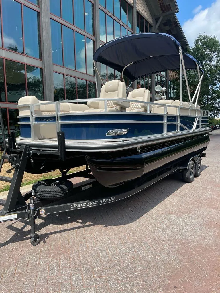 Slide: The Image of 2025 Ranger Reata 220FC pontoon boat on trailer, parked outdoors. - 3