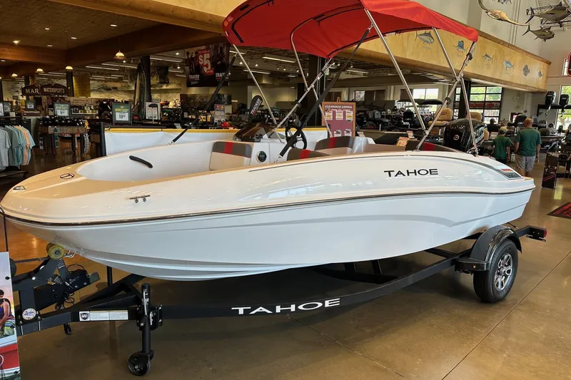 The Image of 2025 Tahoe T16 boat with red canopy displayed indoors on a trailer. - 0