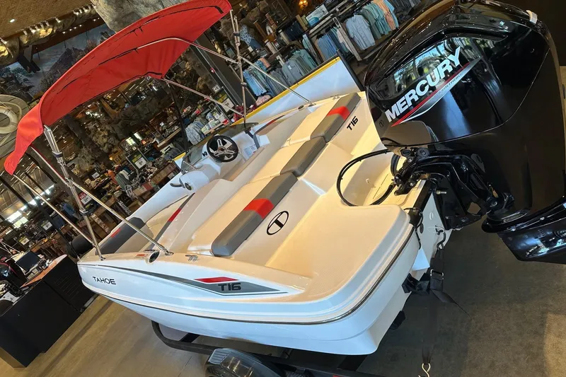 Slide: The Image of 2025 Tahoe T16 boat with Mercury engine, red canopy, displayed indoors. - 2