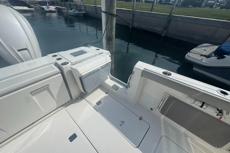 Slide: The Image of 2024 Pursuit S 358 Sport boat interior with storage compartments and dock view. - 10