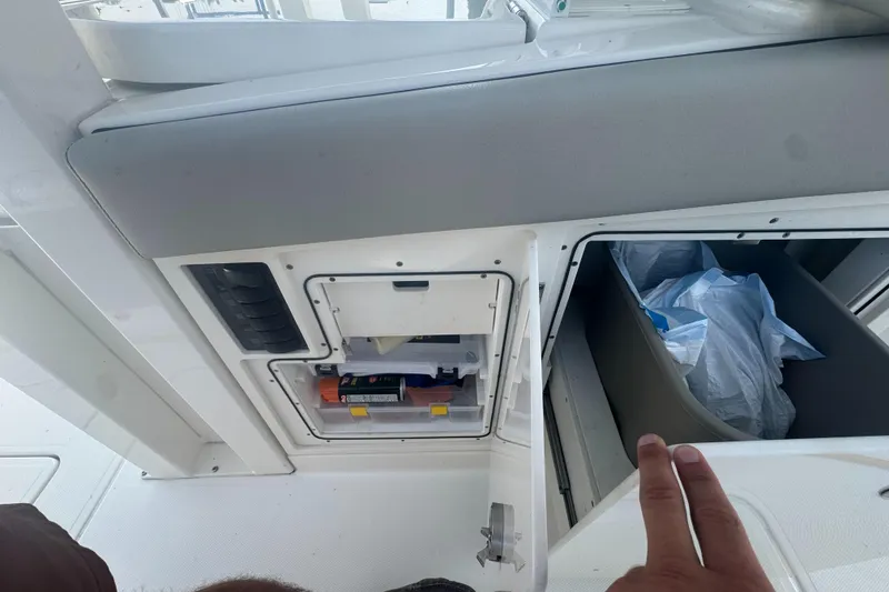 Slide: The Image of 2024 Pursuit S 358 Sport boat storage compartments with supplies and trash bin. - 14