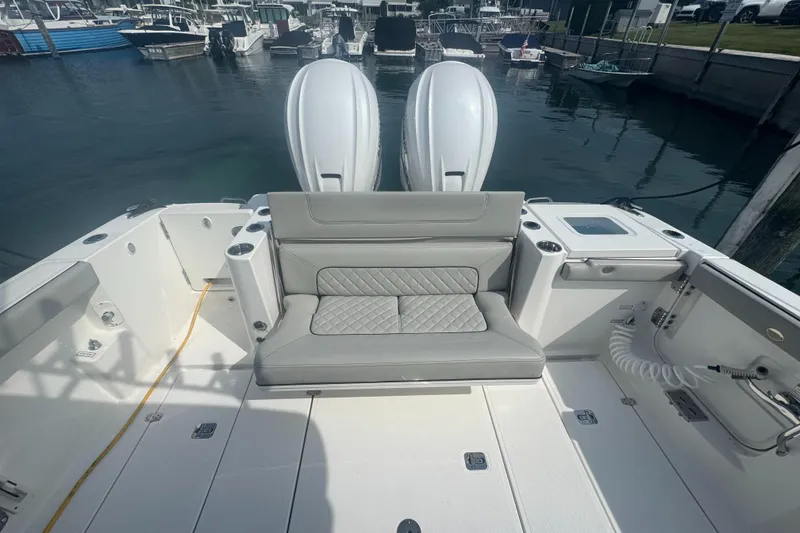 Slide: The Image of 2024 Pursuit S 358 Sport boat interior with seating and dual engines at a marina. - 6