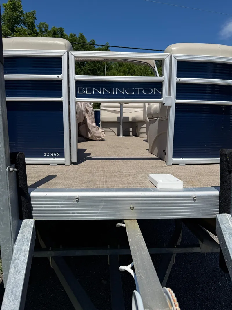 Slide: The Image of 2016 Bennington 22 SX pontoon boat on trailer, featuring open deck and seating. - 3