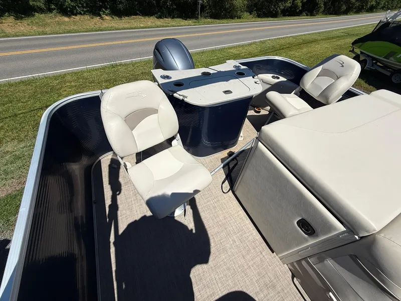 Slide: The Image of 2016 Bennington 22 SX pontoon boat interior with seating and console, parked on grass. - 6