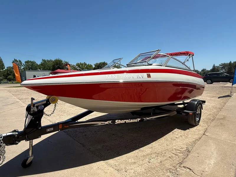 Slide: The Image of 2012 Crownline 18 SS boat on trailer, red and white design, parked outdoors. - 2