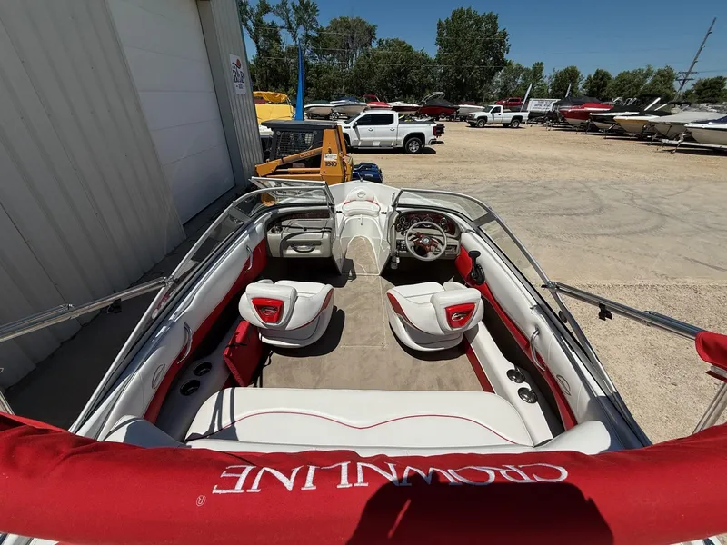 Slide: The Image of 2012 Crownline 18 SS boat interior with red and white seating, parked outdoors. - 9