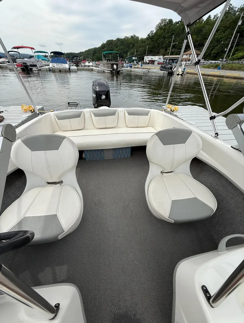Slide: The Image of 2013 Bayliner 160 Bowrider interior with white seating, docked at a marina. - 3