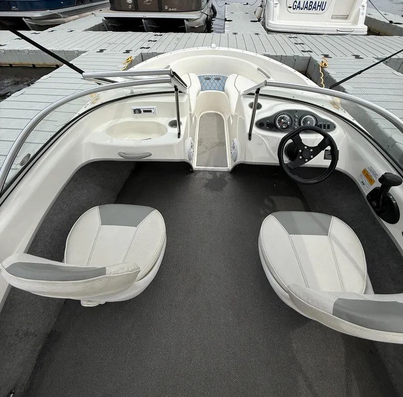 Slide: The Image of 2013 Bayliner 160 Bowrider interior with steering wheel and seating at dock. - 7