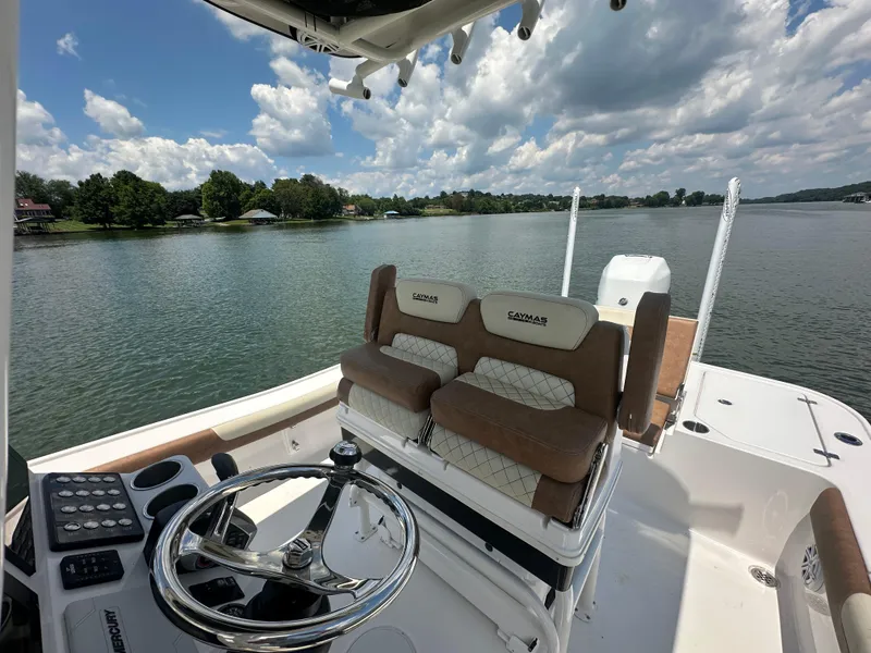 Slide: The Image of 2023 Caymas 26 HB boat interior with steering wheel and seating, on a calm lake. - 12