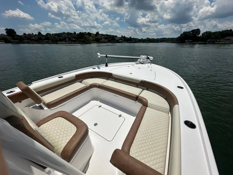 Slide: The Image of 2023 Caymas 26 HB boat with cushioned seating on a calm lake under a cloudy sky. - 14