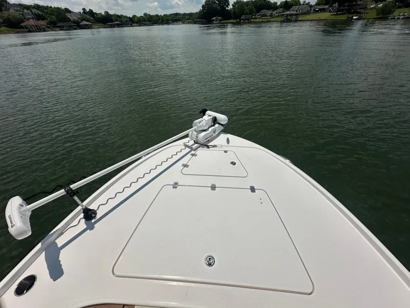 Slide: The Image of 2023 Caymas 26 HB boat on a calm lake, featuring a trolling motor. - 15