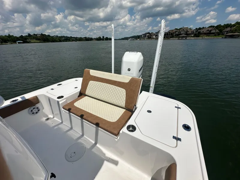 Slide: The Image of 2023 Caymas 26 HB boat with cushioned seating, on a calm lake under a cloudy sky. - 18