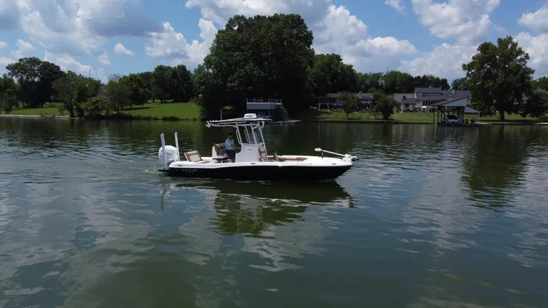 Slide: The Image of 2023 Caymas 26 HB boat cruising on a serene lake under a partly cloudy sky. - 2