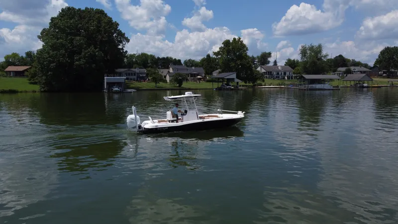Slide: The Image of 2023 Caymas 26 HB boat cruising on a serene lake with houses in the background. - 3