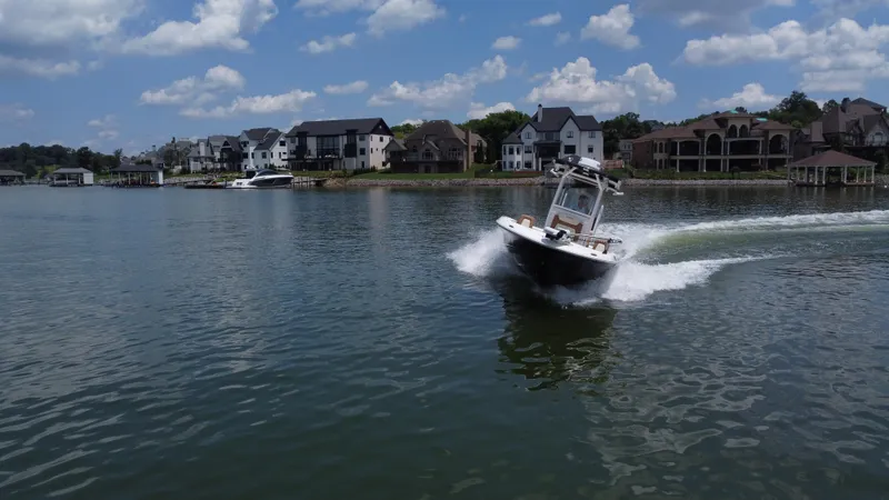 Slide: The Image of 2023 Caymas 26 HB boat cruising on a lake near waterfront homes. - 8