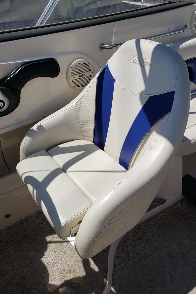Slide: The Image of Captain's chair on 2005 Rinker 232 Captiva Cuddy boat, featuring blue and white upholstery. - 9