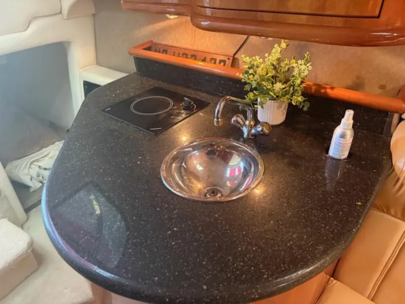 Slide: The Image of 2001 Cobalt 360 yacht kitchenette with black countertop, sink, stove, and decorative plant. - 17