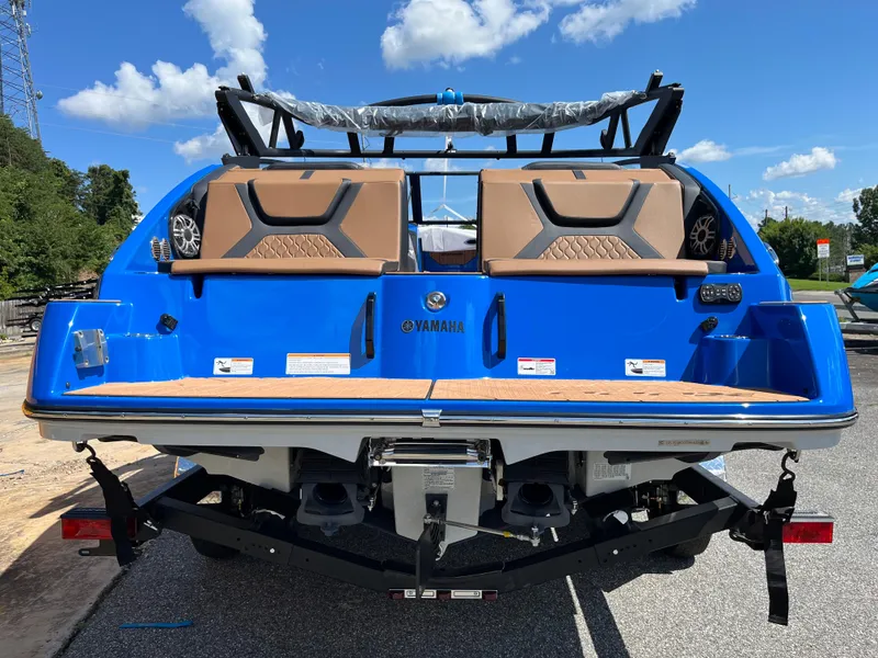 Slide: The Image of 2025 Yamaha Boats 222XD, blue exterior, rear view, parked outdoors under clear sky. - 9