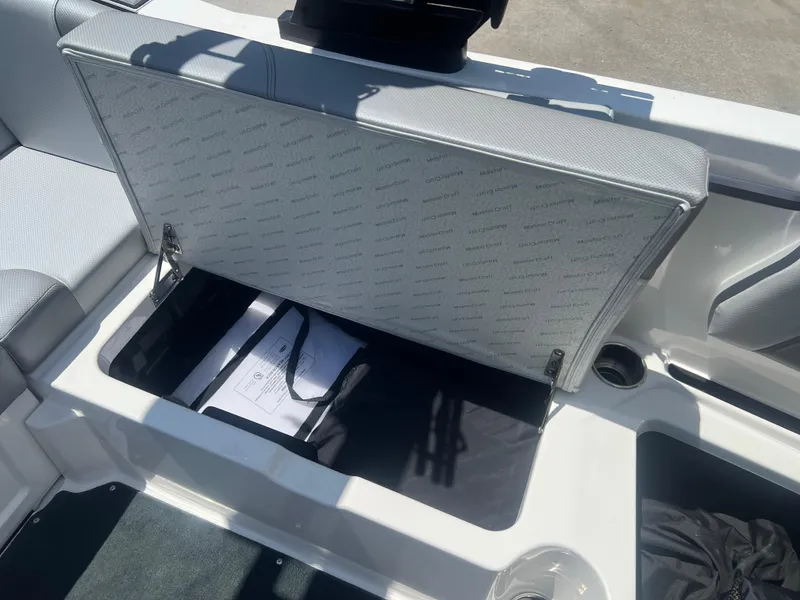 Slide: The Image of Open storage compartment in 2020 MasterCraft NXT20 boat, showing interior space and documents. - 14