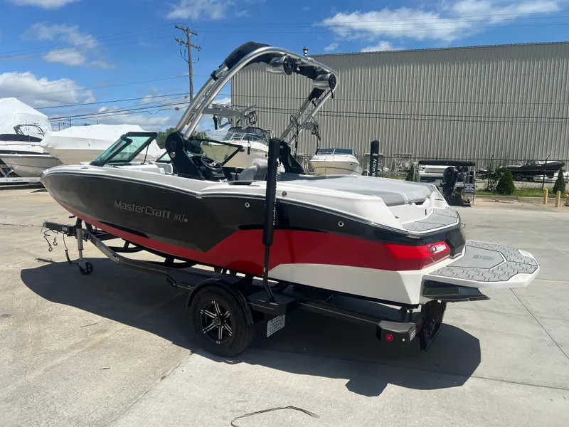 Slide: The Image of 2020 MasterCraft NXT20 boat on trailer, parked outdoors under a clear blue sky. - 3