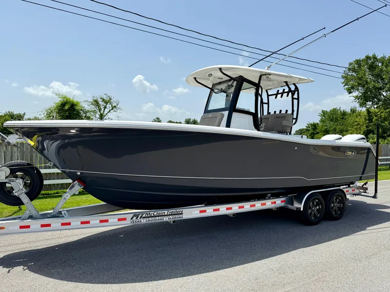 The Image of 2026 Sea Hunt Gamefish 28 Coffin Box boat on trailer, parked on a sunny street. - 1