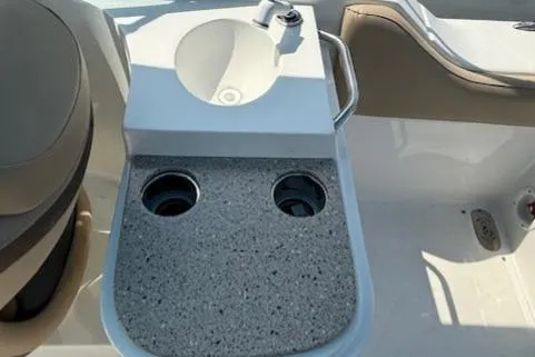 Slide: The Image of 2020 NauticStar 2302 Legacy Dual Console boat interior with sink and cup holders. - 23