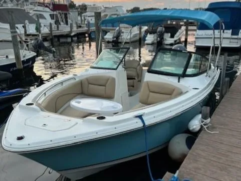 Slide: The Image of 2020 NauticStar 2302 Legacy Dual Console boat docked at marina, featuring blue hull and canopy. - 25