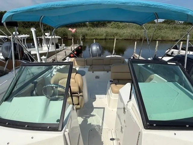 Slide: The Image of 2020 NauticStar 2302 Legacy Dual Console boat with blue canopy docked by the water. - 6