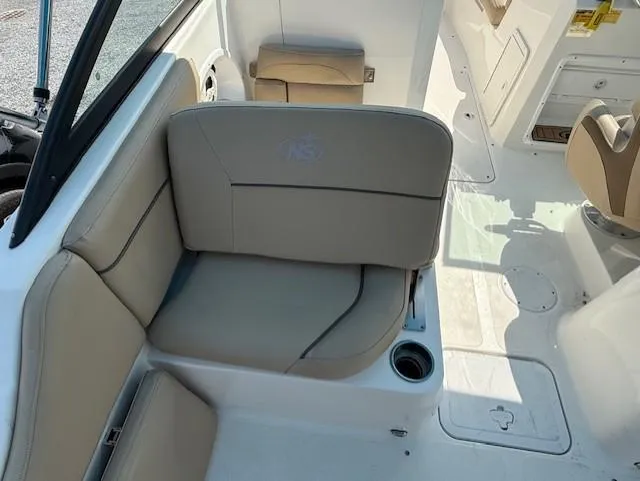 Slide: The Image of 2020 NauticStar 2302 Legacy Dual Console interior with beige seating and cup holder. - 9