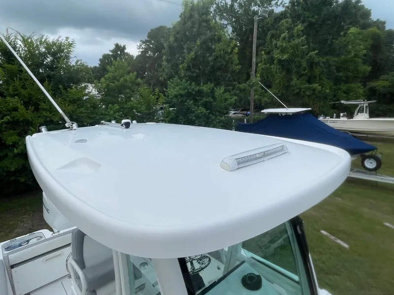 Slide: The Image of 2023 Everglades 235 Center Console boat with sleek white roof, surrounded by greenery. - 13