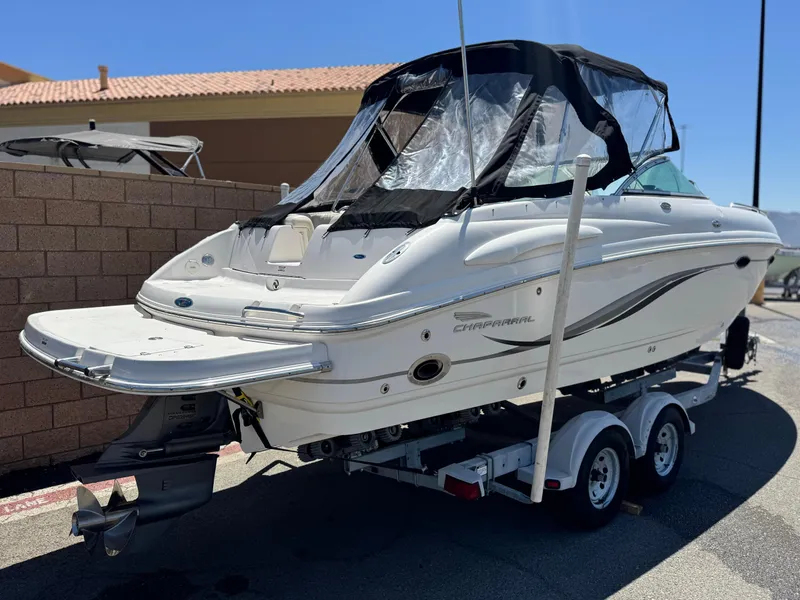 Slide: The Image of 2004 Chaparral 265 SSi boat on trailer, white exterior, black canopy, parked outdoors. - 5