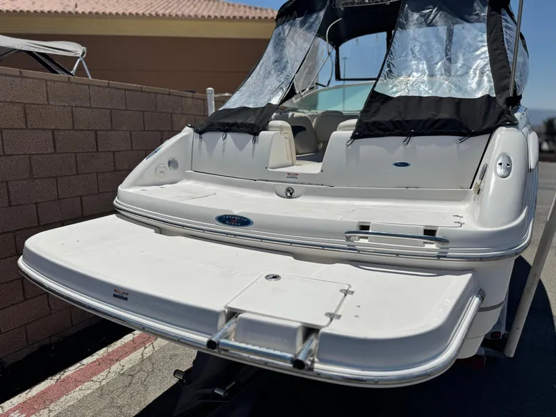 Slide: The Image of 2004 Chaparral 265 SSi boat with swim platform and canopy, parked near a brick wall. - 6