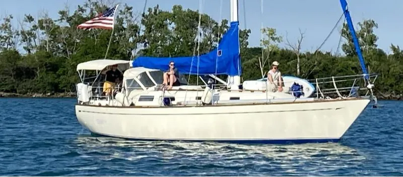The Image of 1980 CAL 39 MK II Sloop sailing with people onboard, American flag, calm waters, sunny day. - 0