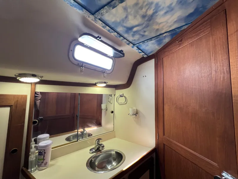 Slide: The Image of 1980 CAL 39 MK II Sloop bathroom with sink, mirror, and wooden cabinetry. - 10