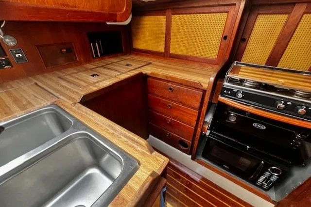 Slide: The Image of 1980 CAL 39 MK II Sloop interior kitchen with wooden cabinetry, sink, and stove. - 12