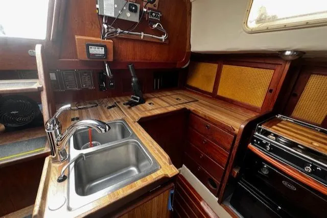 Slide: The Image of 1980 CAL 39 MK II Sloop interior kitchen with wooden cabinetry, dual sink, and stove. - 13