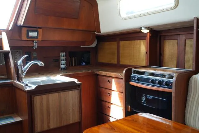 Slide: The Image of Interior of 1980 CAL 39 MK II Sloop, featuring a wooden kitchen with stove and sink. - 14