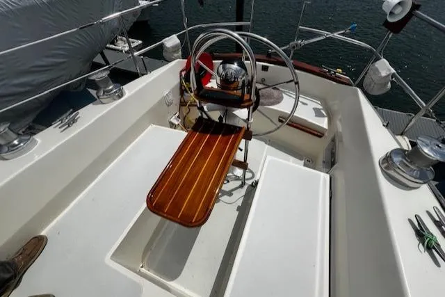 Slide: The Image of 1980 CAL 39 MK II Sloop cockpit with wooden bench and steering wheel, docked by water. - 36