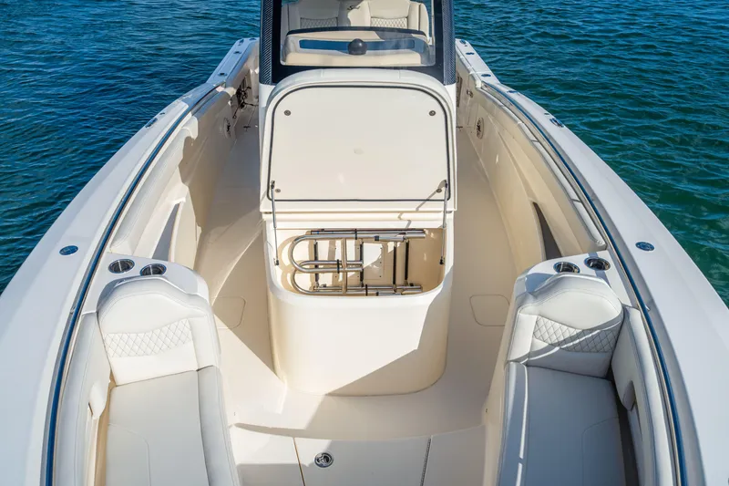 Slide: The Image of 2026 Scout 288 LXF boat interior with seating and storage, on calm blue water. - 13
