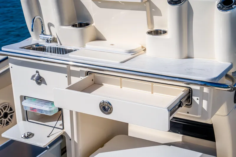 Slide: The Image of 2026 Scout 288 LXF boat kitchen area with sink, storage, and countertop. - 26