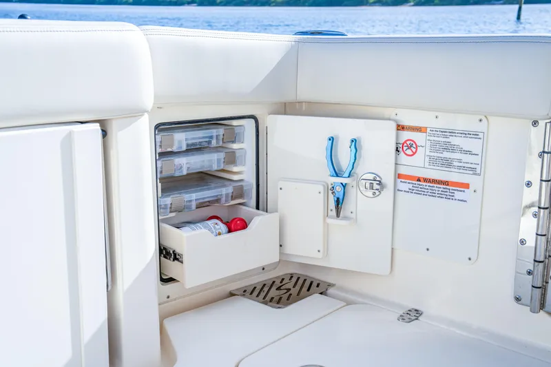 Slide: The Image of 2026 Scout 288 LXF boat storage compartment with tools and safety instructions. - 34