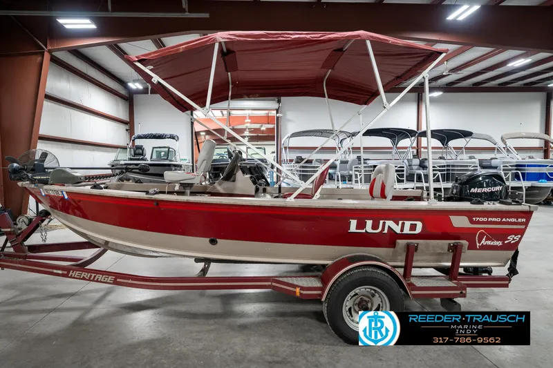 Slide: The Image of 1997 Lund 1700 Pro Angler boat with canopy on trailer in showroom. - 10