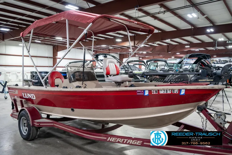 Slide: The Image of Red 1997 Lund 1700 Pro Angler boat with canopy, displayed indoors on a trailer. - 5
