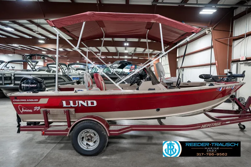 Slide: The Image of 1997 Lund 1700 Pro Angler boat with red canopy on trailer in showroom. - 6