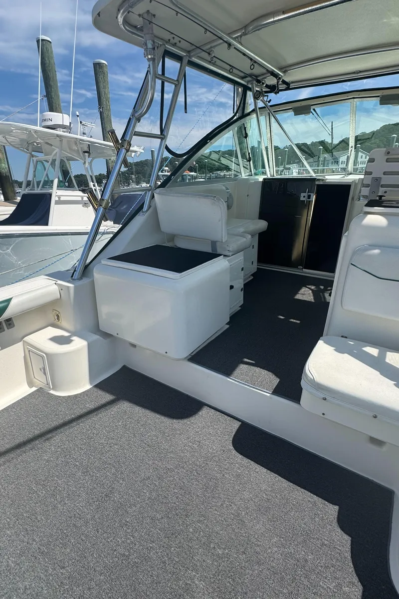 Slide: The Image of 2002 Pursuit 3000 Express boat interior with seating and helm, docked under clear skies. - 10