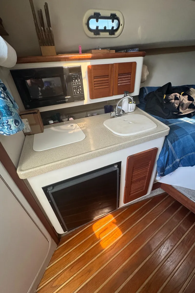 Slide: The Image of 2002 Pursuit 3000 Express cabin kitchen with sink, microwave, and wooden flooring. - 21