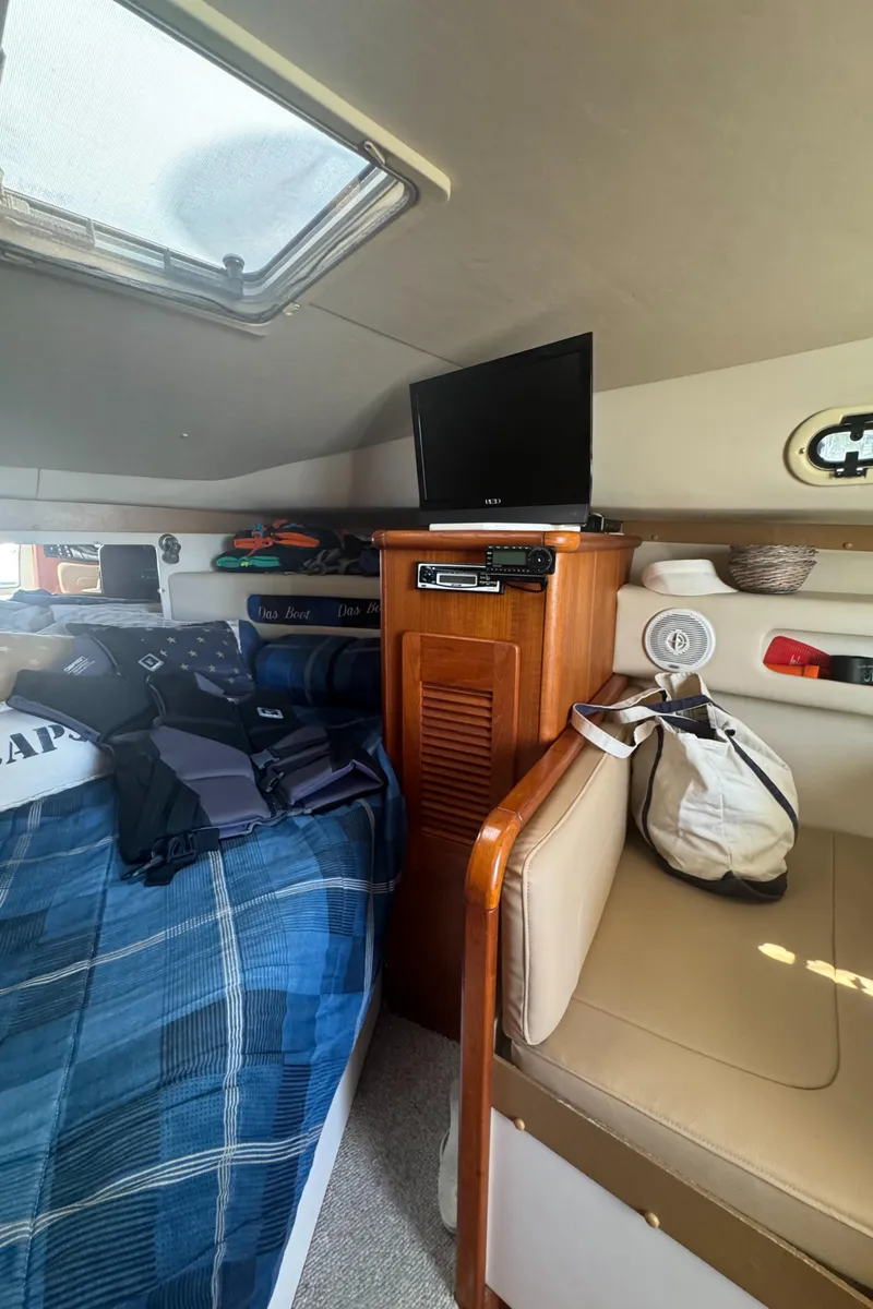 Slide: The Image of Interior cabin of a 2002 Pursuit 3000 Express boat with bed, TV, and seating area. - 23