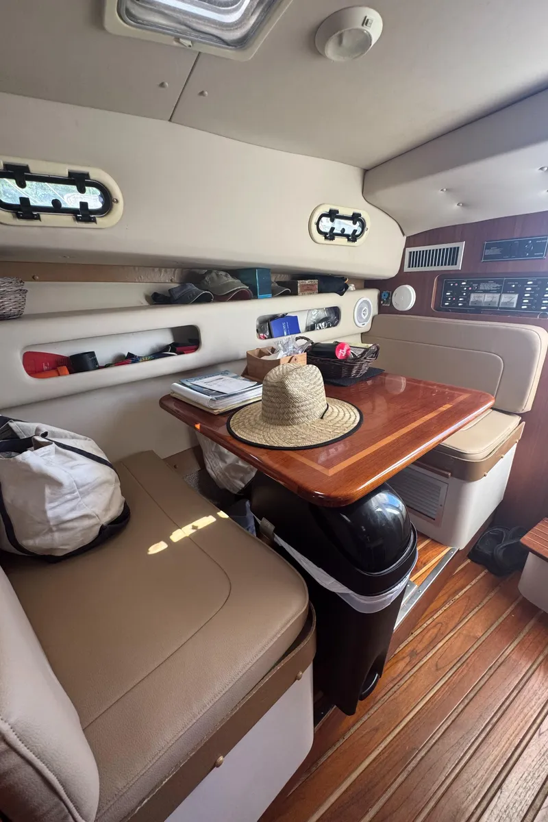 Slide: The Image of Interior of 2002 Pursuit 3000 Express boat with wooden table and seating area. - 27